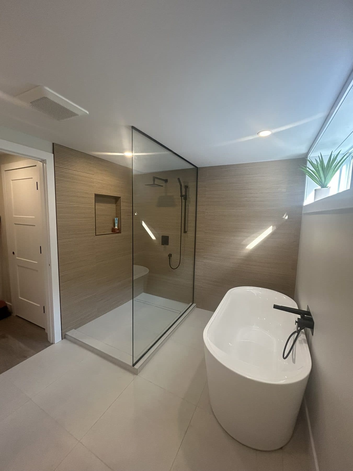 Tempered glass shower next to a freestanding tub