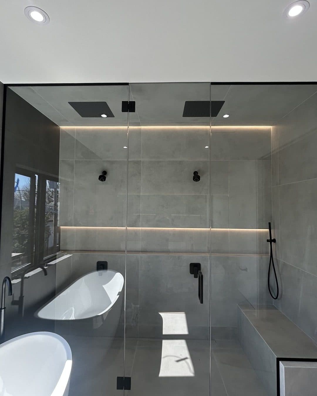 Grande douche vitrée dans une salle de bain foncée