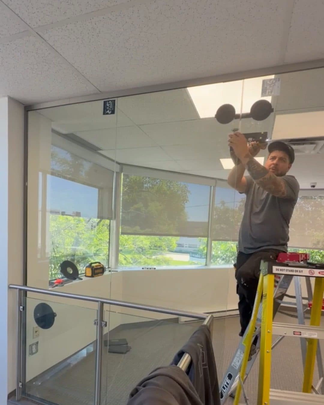 Installer on a stepladder fixing a glass panel