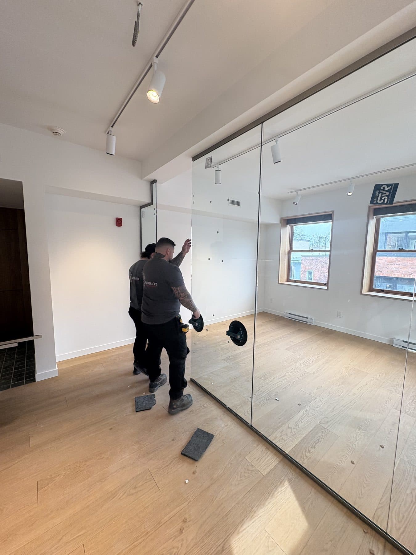 Installateur de Vitrenière qui pose une cloison vitrée dans un bureau